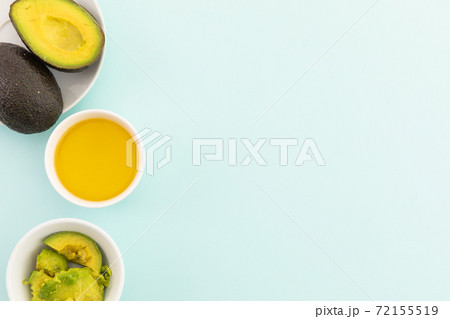 Bowls of halved avocados and dressing on blue background 72155519