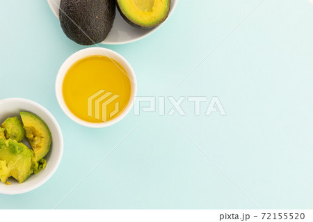 Bowls of halved avocados and dressing on blue background 72155520