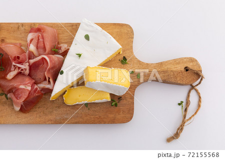 Cheese and ham on wooden board on white background 72155568