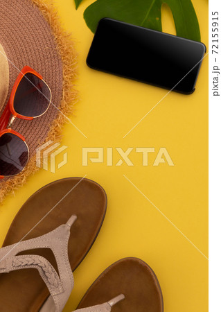 Sunglasses, flip flops, sunhat and smartphone on yellow background Sunglasses, flip flops, sunhat and smartphone on yellow background 72155915