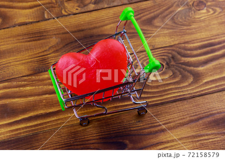 Shopping cart with big red heart on wooden background. Valentines Day concept Shopping cart with big red heart on wooden background. Valentines Day concept 72158579
