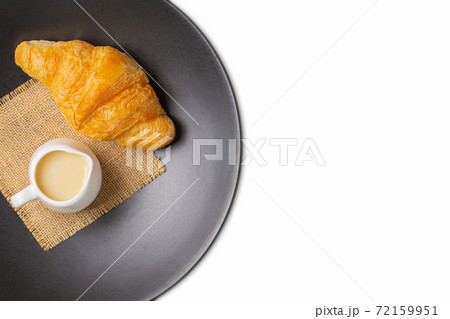 Croissant on black plate with sweetened condensed milk and sackcloth  72159951
