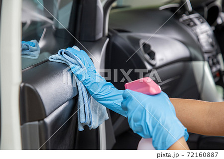 Hand wearing rubber gloves and using a blue microfiber cloth clean the car interior. Cleaning car  interior concept. 72160887