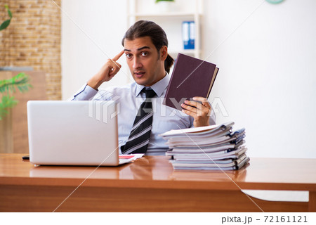 Young male student employee reading book at workplace Young male student employee reading book at workplace 72161121