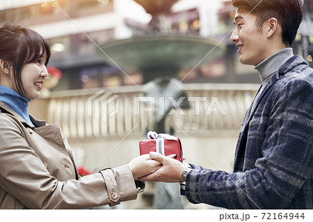 young asian woman ceceiving a christmas or birthday present from husband or boyfriend 72164944