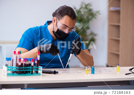 Young male biochemist testing blood samples in pandemic concept 72166163