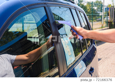 The man takes the remnants of water from the glass after washing the car at the self-service car wash, the car is blue. 72166376