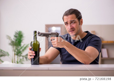 Young male alcoholic committing suicide at home 72168198
