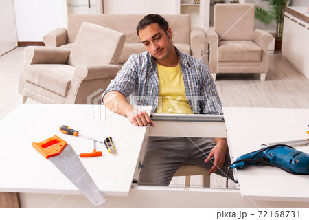 Young male carpenter repairing furniture at home 72168731