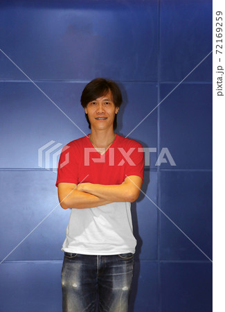 Man wearing Indonesia flag pattern shirt and cross one's arm on the blue wall background, Man wearing Indonesia flag pattern shirt and cross one's arm on the blue wall background, 72169259