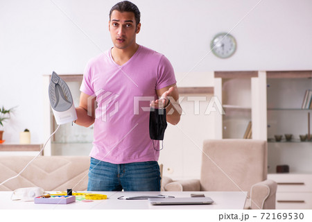 Young male tailor ironing mask during pandemic 72169530