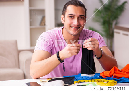 Young male tailor sewing masks at home during pandemic Young male tailor sewing masks at home during pandemic 72169551