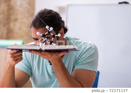 Young male student physicist studying molecular model at home Young male student physicist studying molecular model at home 72171137