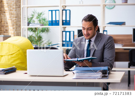 Young male employee looking after newborn at workplace Young male employee looking after newborn at workplace 72171383