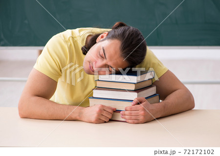 Young male student preparing for exams in the classroom Young male student preparing for exams in the classroom 72172102
