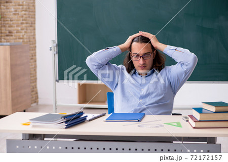 Young male teacher in front of green board Young male teacher in front of green board 72172157