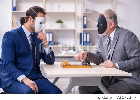 Two businessmen playing chess wearing masks 72172247