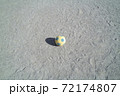 公園の砂地に転がるサッカーボールに当たる光と伸びる影 72174807