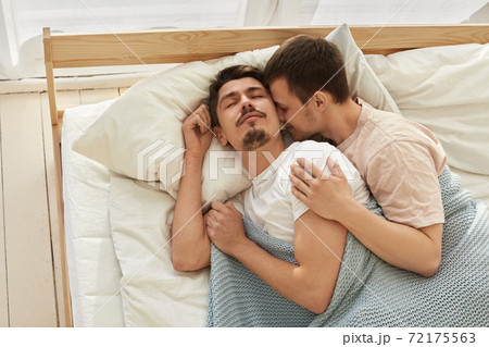 Happy gay couple lying on bed at home 72175563