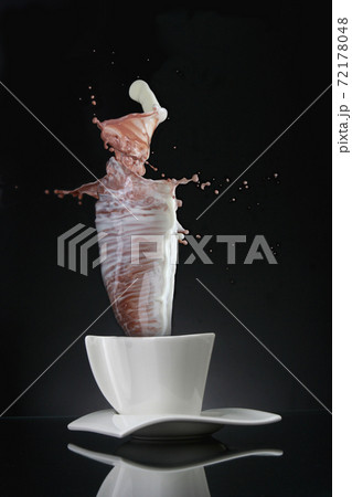White cup with splash of milk and coffee on black. White cup with splash of milk and coffee on black. 72178048