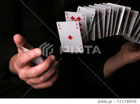 Man making magic trick with playing card on black. 72178049