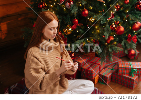 High-angle shot of dreamy young woman writing wish list for new year on background of Christmas tree 72178172
