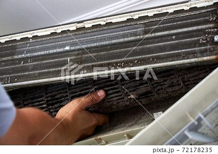 A service worker pulls a dirty turbine out of an indoor unit of the air conditioner A service worker pulls a dirty turbine out of an indoor unit of the air conditioner 72178235