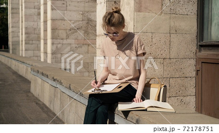 Young woman in sunglasses preparing for the exam outside, university building Young woman in sunglasses preparing for the exam outside, university building 72178751