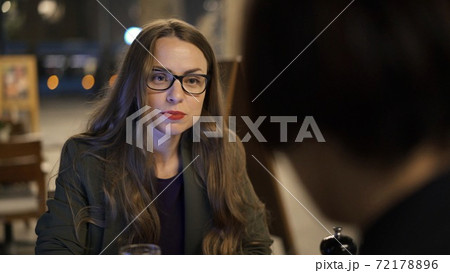 Woman in eyeglasses talking with her friend, discussing plans drinking beer Woman in eyeglasses talking with her friend, discussing plans drinking beer 72178896