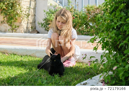 Girl playing with big black cat, outdoor, petting an animal 72179166