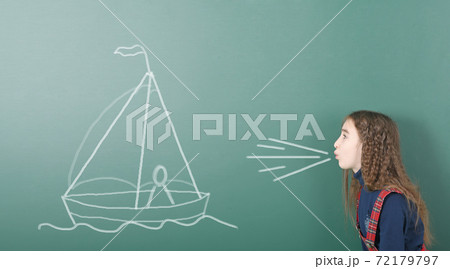 Pre-adolescent girl blowing on painted sailing ship Pre-adolescent girl blowing on painted sailing ship 72179797