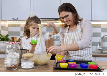 Mother and daughter cooking muffins together in home kitchen Mother and daughter cooking muffins together in home kitchen 72180194