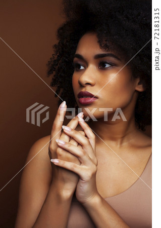 pretty young african american woman with curly hair posing cheerful gesturing on brown background, lifestyle people concept pretty young african american woman with curly hair posing cheerful gesturing on brown background, lifestyle people concept 72181315
