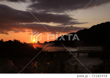 日向灘を赤く染める朝陽を顔に受けて走る通勤列車のキハ40 72182458