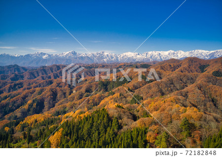 小川村発地から見る冠雪した白馬連山と紅葉の里山の山並み　長野県小川村（ドローンによる空撮） 72182848