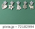 Christmas minimal flat lay composition. Border made of wooden Xmas decorations in shape of stars, xmas tree, snowflake and deer on green background. New Year, winter holidays. Top view, copy space 72182994