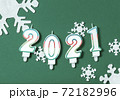 2021 New Year flat lay composition. Candles in shape of figures, white snowflakes decorations on green background. Christmas concept. Top view 72182996