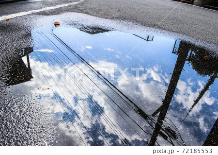 雨上がりの水溜まりに映る青空の写真素材