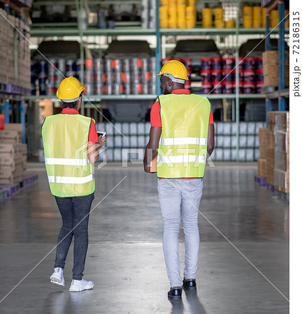 Back of African American warehouse man and woman discuss together during work 72186315