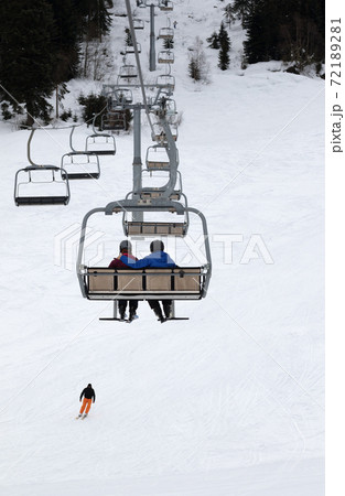 Two skiers on chair-lift in gray winter day 72189281