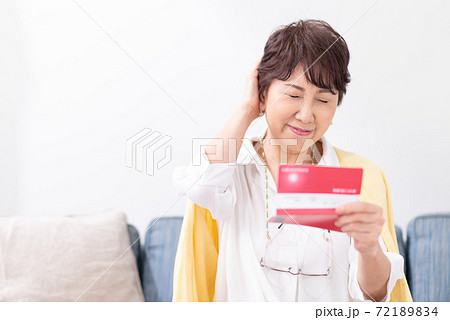 通帳を見て悩む女性 72189834