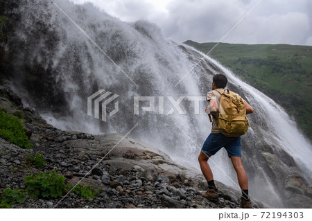 Waterfall Landscape and male Traveler enjoying waterfall view. 72194303