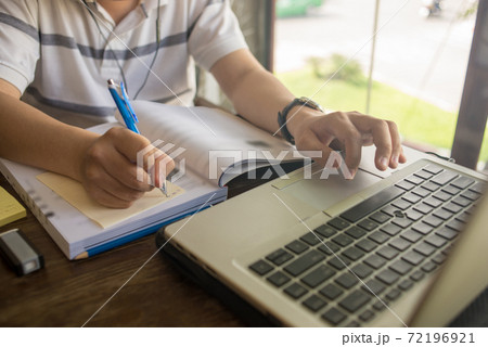 Student writing note and using laptop while studying 72196921