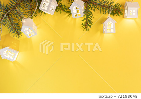 Christmas Or New Year yellow background with frame of green fir branches and luminous Xmas lights on bright yellow with copy space. Xmas decorations. Top view. Horizontal orientation. 72198048