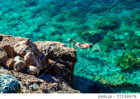 Nice view of the sea. Calm clear sea. At the bottom are large stones. The diver floats on the surface. View from above Nice view of the sea. Calm clear sea. At the bottom are large stones. The diver floats on the surface. View from above 72198676