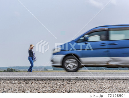 Blurred silhouettes of a fast-moving car and a woman standing on the side of the road Blurred silhouettes of a fast-moving car and a woman standing on the side of the road 72198904