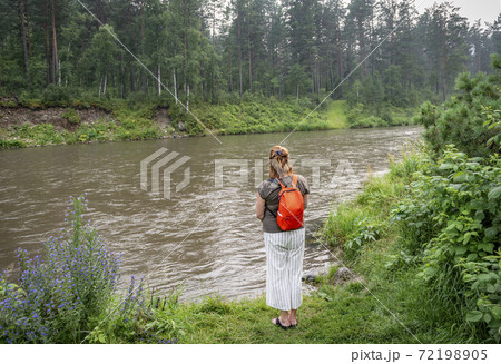 Woman admiring the flow of the river against the forest Woman admiring the flow of the river against the forest 72198905