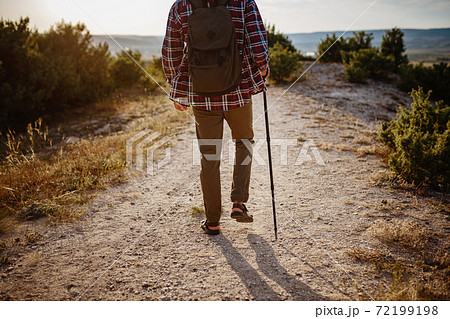 man hiking in the mountains using pole and looking away 72199198