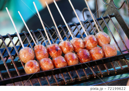 Thai sausage with wood stick grilling on the metal grill grate in the stove.  72199622