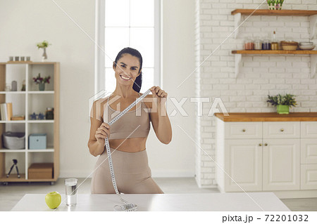 Portrait of a female sports coach and dietitian standing with a tape measure in her hands. Portrait of a female sports coach and dietitian standing with a tape measure in her hands. 72201032